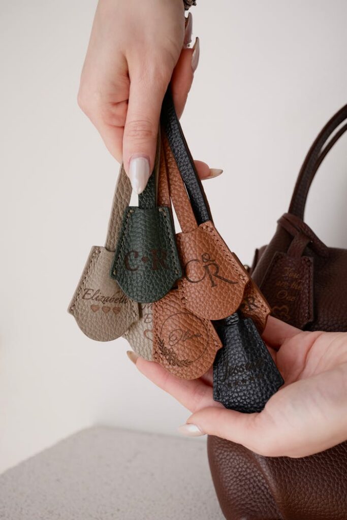pexels-photo-20364515 Female hands showcasing a selection of elegant leather bag tags in various colors indoors.