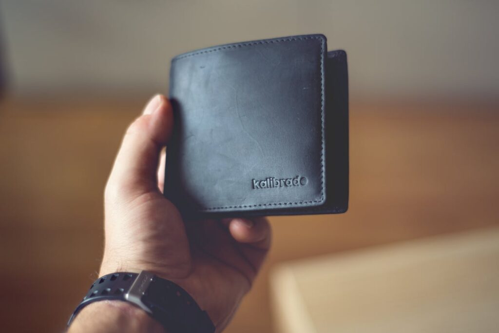 pexels-photo-4568373 Close-up of a stylish black leather wallet held by a person, showcasing design.